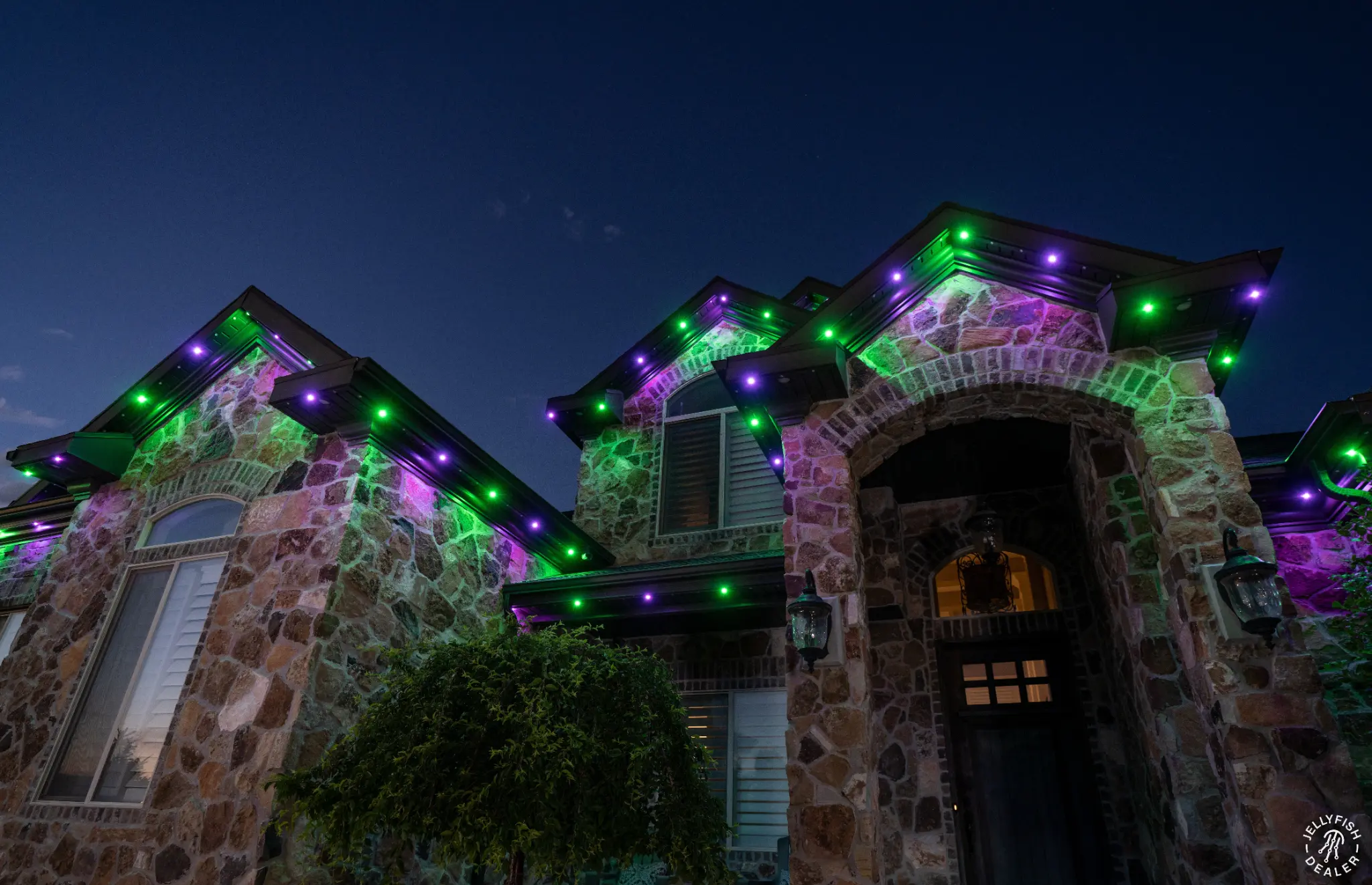 Home exterior illuminated in colorful permanent outdoor roofline lighting
