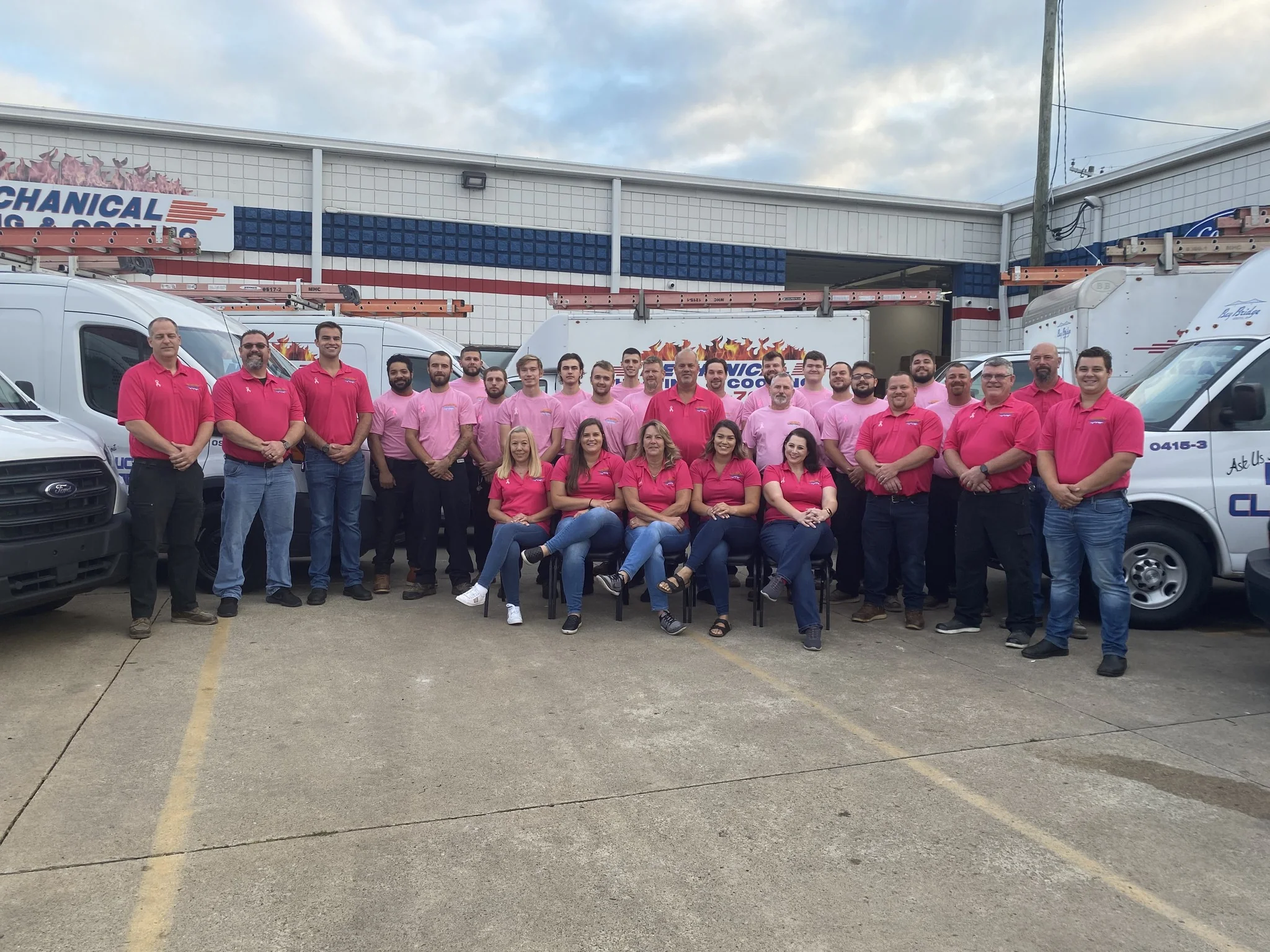 Mechanical Heating, Cooling & Electrical team members gathered in front of service vehicles