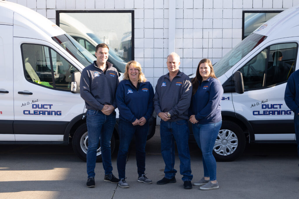 Mechanical Heating and Cooling team members standing in front of service vans, promoting duct cleaning services, showcasing commitment to HVAC expertise and customer service.