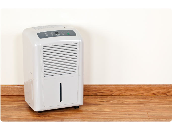 Dehumidifier appliance on wooden floor, illustrating humidity control for indoor air quality in homes.