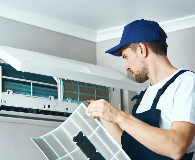 Technician performing maintenance on an air conditioning unit, inspecting and replacing the filter for optimal HVAC performance and indoor air quality.