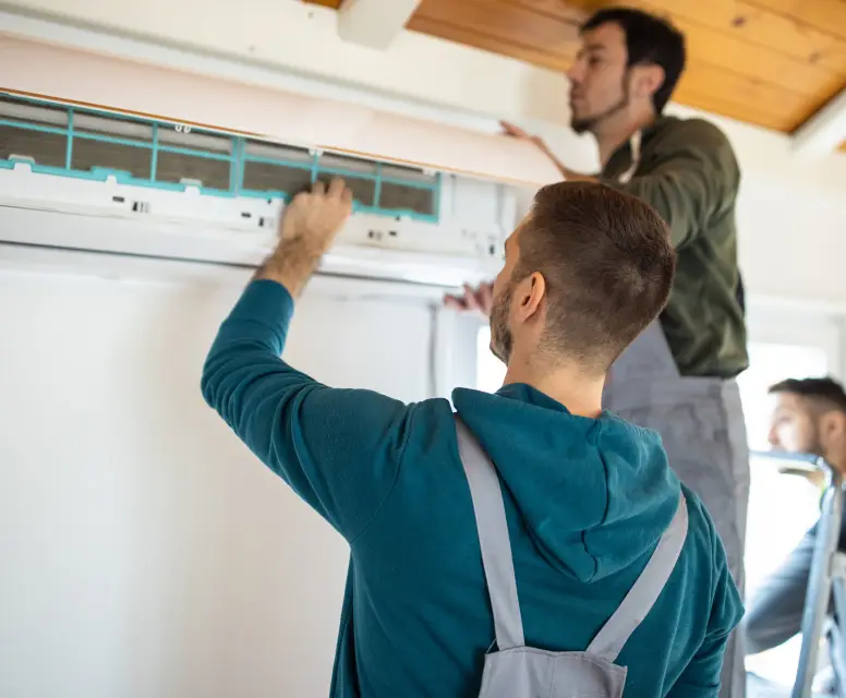 Technicians installing an air conditioning unit in a residential setting, emphasizing HVAC services in Dearborn Heights.