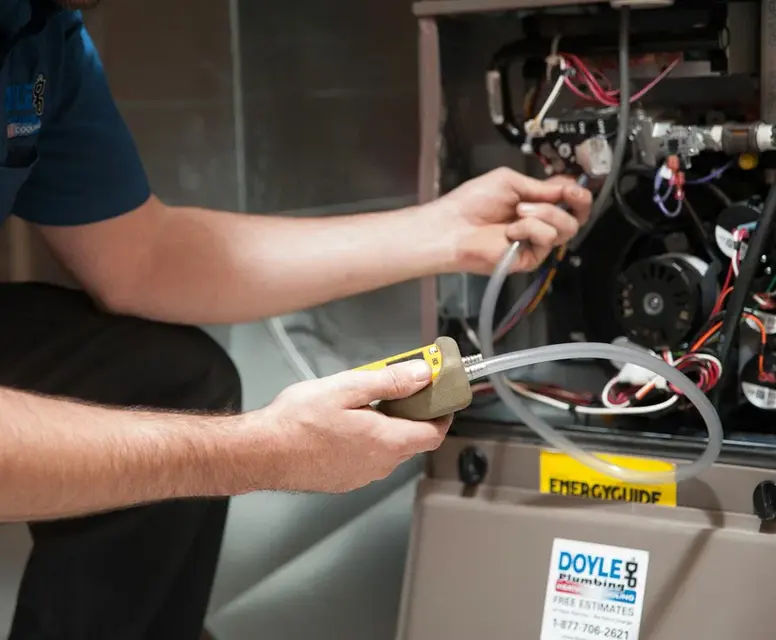 Technician performing maintenance on a heating system, inspecting internal components and using a gas analyzer, highlighting HVAC service for furnaces and boilers.