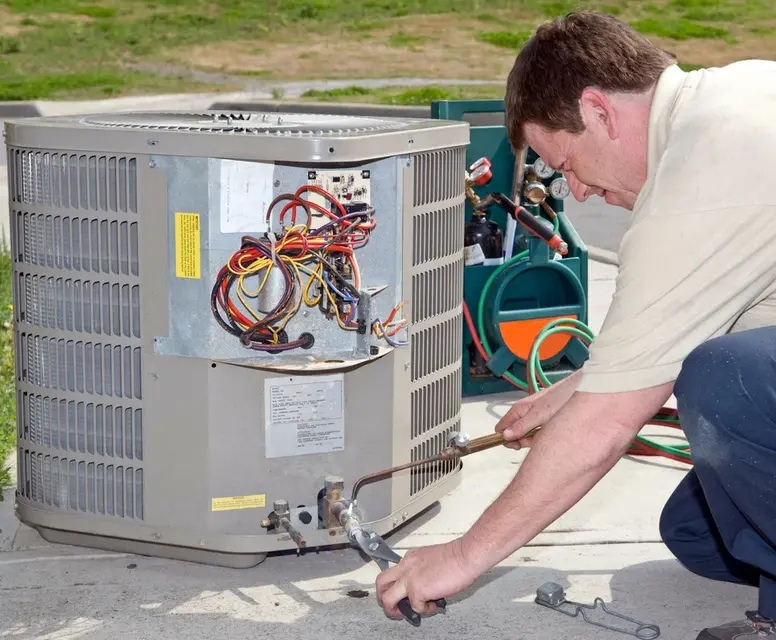 Technician repairing an air conditioning unit, showcasing HVAC service expertise relevant to Mechanical Heating & Cooling's offerings in Garden City.