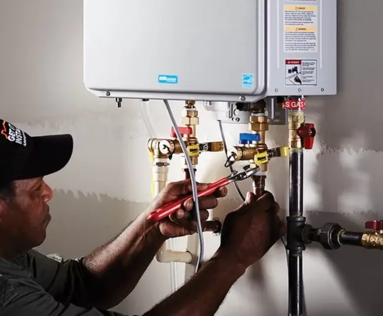 Technician installing a tankless water heater, adjusting plumbing connections and ensuring proper setup for energy-efficient hot water solutions in Canton.
