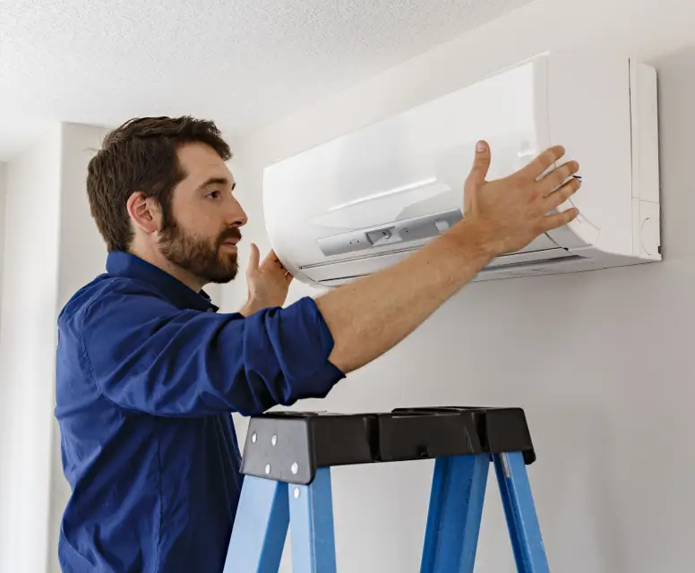 Technician installing a new air conditioning unit on a wall, emphasizing HVAC services for residential comfort in Romulus, MI.