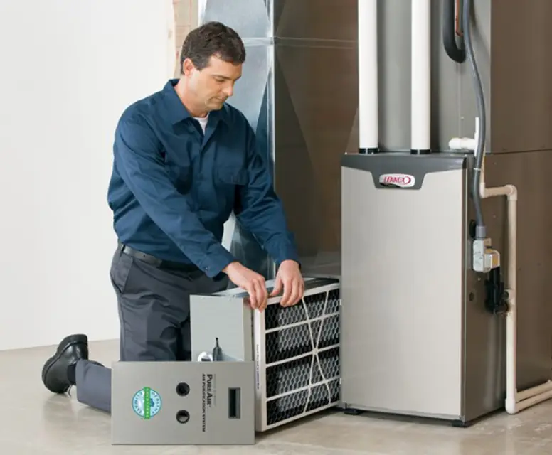 Technician performing maintenance on a high-efficiency furnace, focusing on filter replacement, in a residential setting.