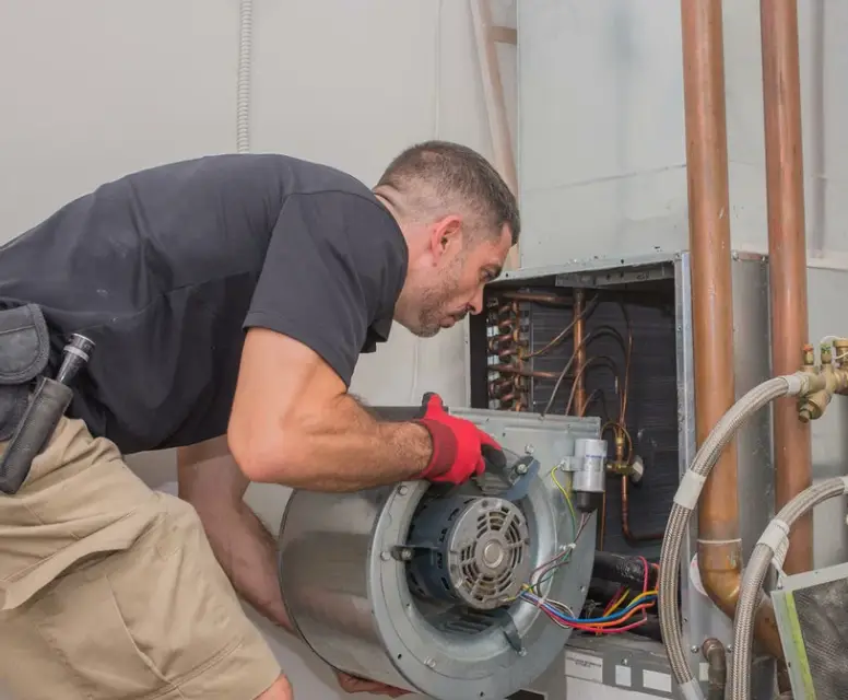 HVAC technician performing maintenance on air conditioning unit, focusing on motor and components for optimal cooling efficiency.