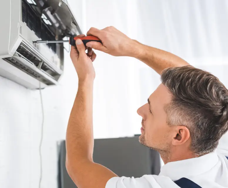 Technician repairing an air conditioning unit, demonstrating HVAC service expertise relevant to installation and maintenance.